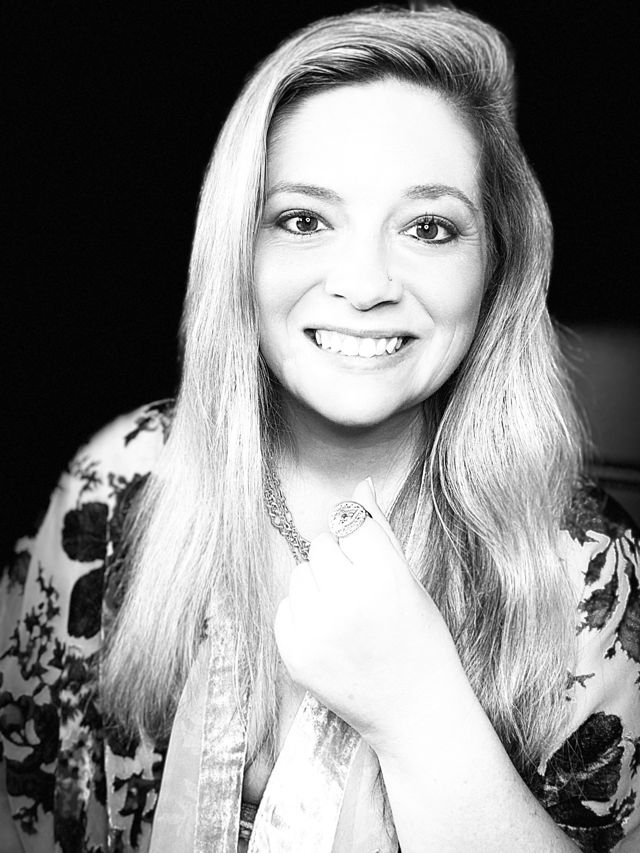 Author Kendall Evans smiling, with long hair and a floral velvet wrap